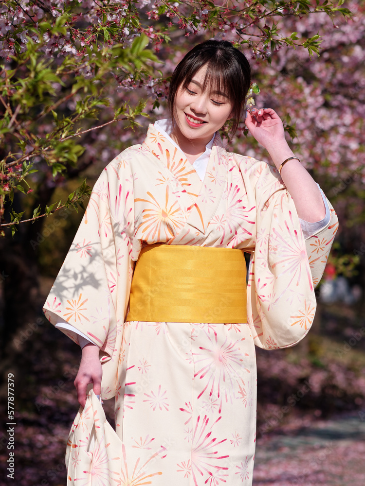Portrait of beautiful young Chinese girl in Japanese kimono posing eyes closed with blossom cherry flowers background in spring garden, beauty, emotion, lifestyle, expression and people concept.
