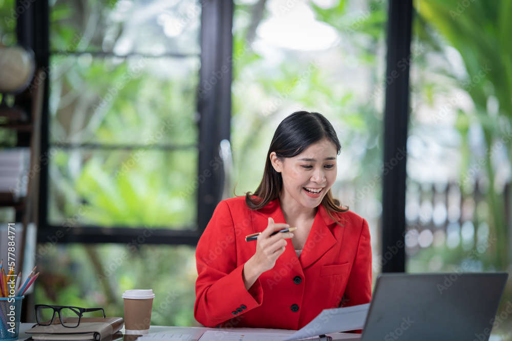 Attractive young smiling Asian woman in smart casual wear and holding smart phone looking at camera while leaning on desk in creative office Confident business expert Attractive young smiling Asian woman in smart casual wear and holding smart phone looking at camera while leaning on desk in creative office Confident business expert