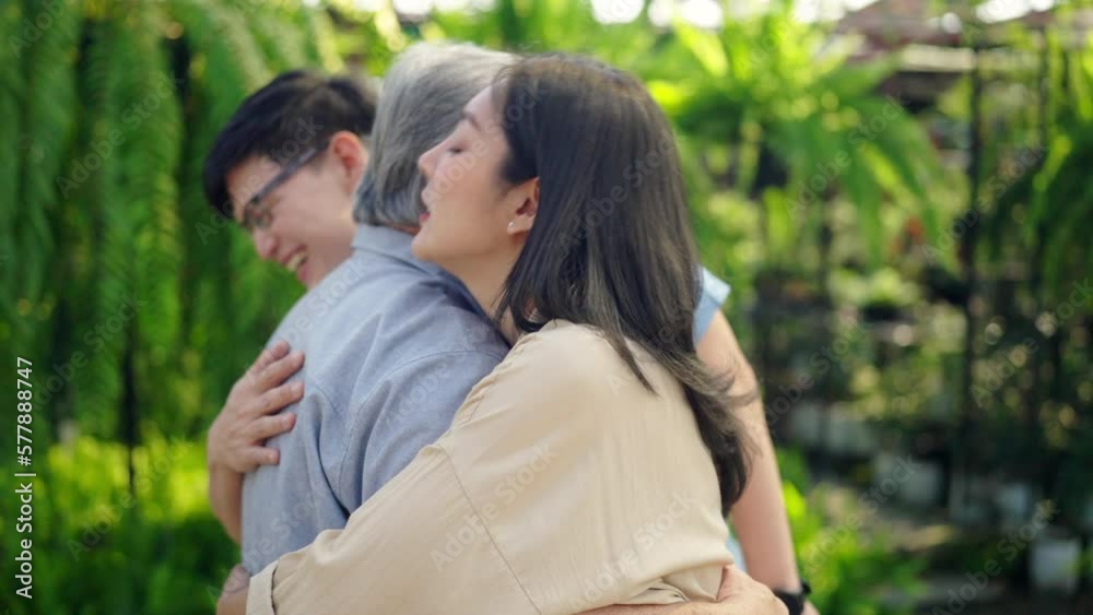 Asian family relationship and old people health care concept. Adult couple meeting and hugging elderly father at plant shop. Retired man enjoy outdoor activity with daughter and son on summer vacation Asian family relationship and old people health care concept. Adult couple meeting and hugging elderly father at plant shop. Retired man enjoy outdoor activity with daughter and son on summer vacation