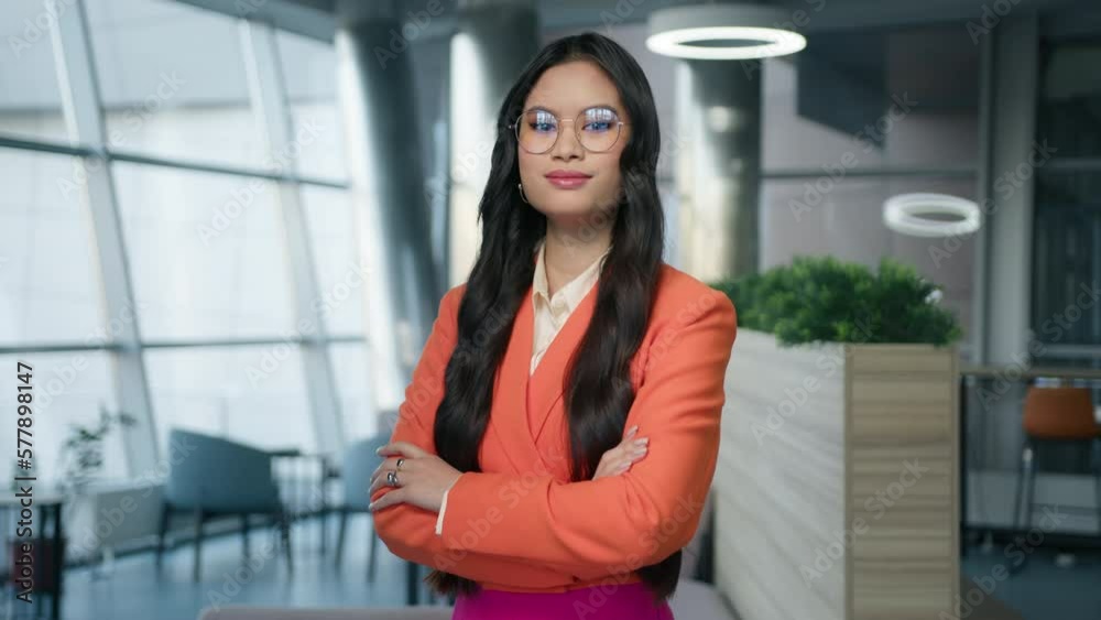 Strong lady boss in eyewear, female leader multiracial woman in modern jacket posing crossing arms looking at camera corporate office. Millennial smart asian 20s successful confident businesswoman 4K Strong lady boss in eyewear, female leader multiracial woman in modern jacket posing crossing arms looking at camera corporate office. Millennial smart asian 20s successful confident businesswoman 4K