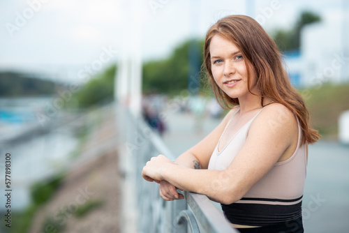 the girl stands at the metal fence and leans on it, the fence is near the river Free Download the girl stands at the metal fence and leans on it, the fence is near the river - GFXLoad