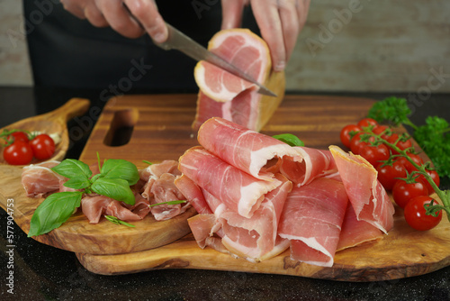 Male hands cutting with sharp knife traditional Spanish dry smoked ham leg photo