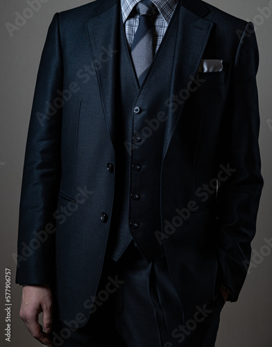 Elite businessman in a luxury custom-made suit against gray background.
