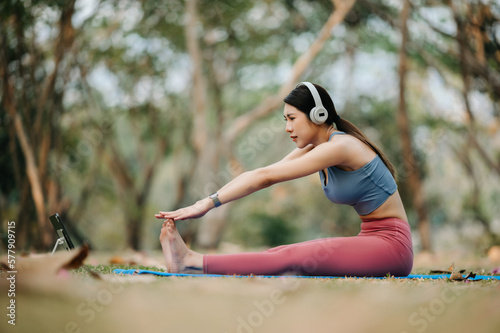 Portrait of young woman with closed eyes sitting in lotus position on yoga mat in the garden. sun light