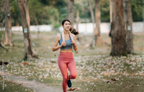 Fototapeta Naklejka Na Ścianę i Meble -  Young sporty woman running in green park.Sport lifestyle. Motion blur. in sun light