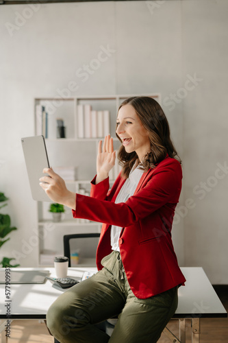  Working woman concept a female manager attending video conference and holding tablet, smatrphone and cup of coffee in office
