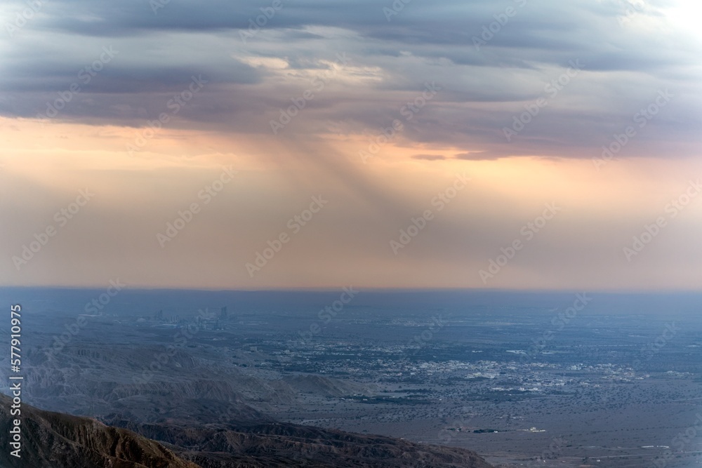 A landscape photo of cloud formation from hilltop showing flowing rain down on the city.