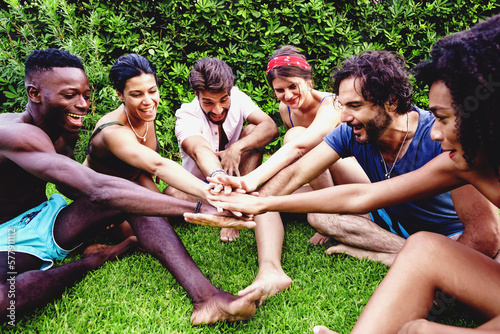 Friends bonding in a multicultural group - Unity in diversity: friends holding hands in a circle