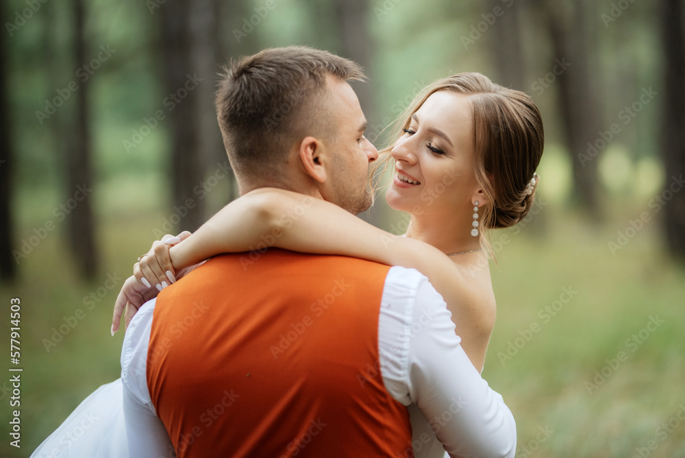 young couple bride in a white short dress and groom in a gray suit in a pine forest young couple bride in a white short dress and groom in a gray suit in a pine forest