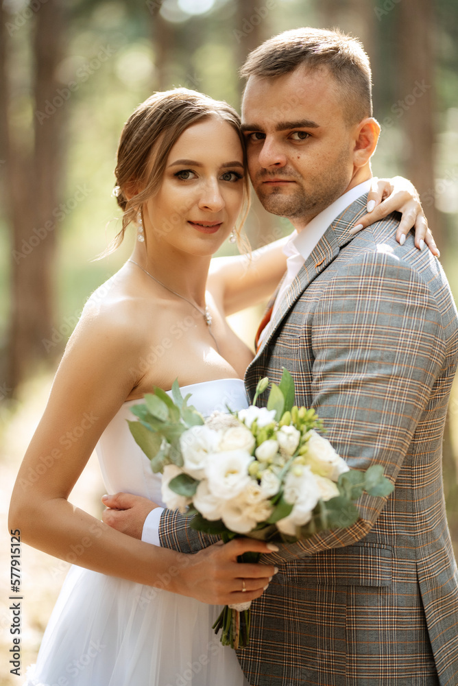 young couple bride in a white short dress and groom in a gray suit in a pine forest young couple bride in a white short dress and groom in a gray suit in a pine forest