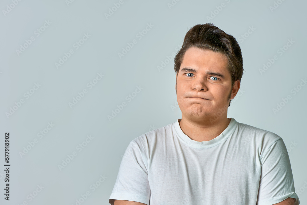 Fototapeta premium a frowning man on a gray background, copy space