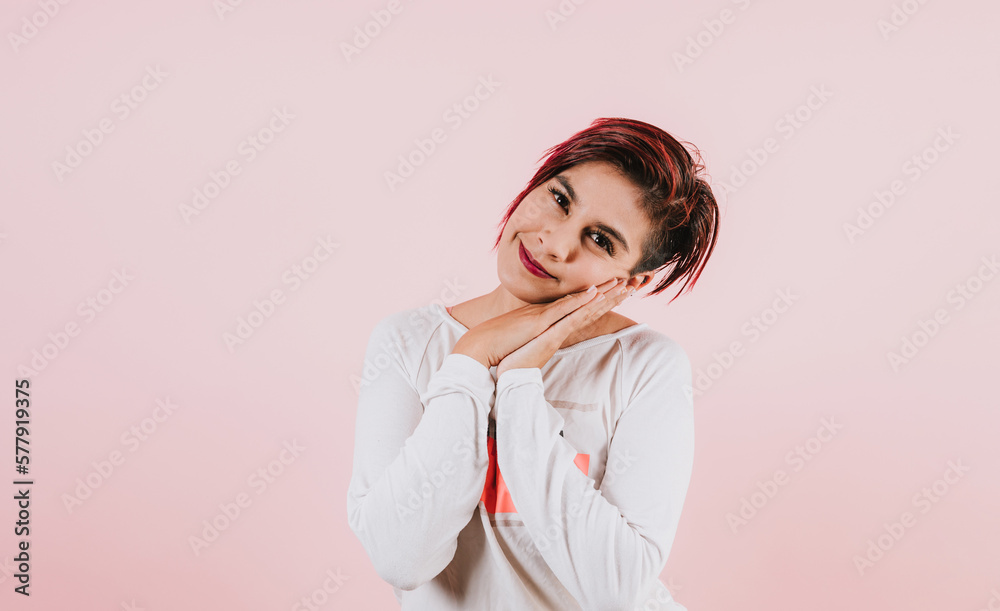 portrait of young hispanic girl posing with face expressions on coral pink background in Mexico Latin America	