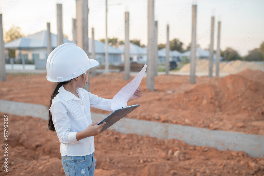 Fototapeta premium Engineer kid concept,Asian little girl wear engineer uniform working at site of building