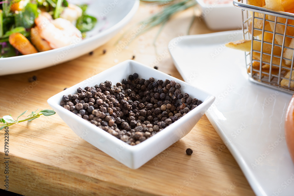 A view of a condiment cup of black peppercorns.