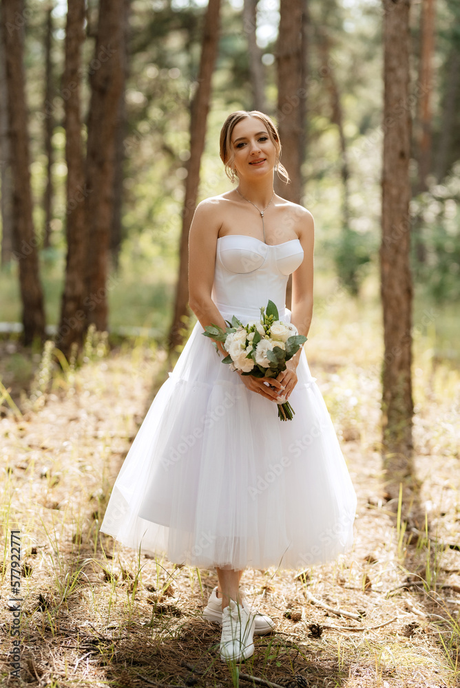 young bride in a white short dress in a spring pine forest young bride in a white short dress in a spring pine forest
