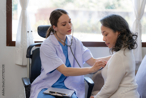 Female doctor is using a stethoscope to measure the heart rate of an Asian female patient.