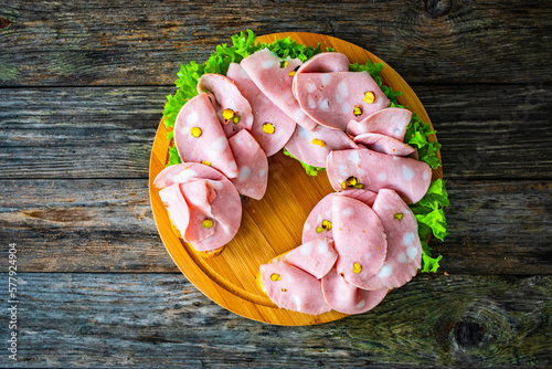 фотографія Big sandwich with mortadella with pistachios and lettuce on wooden table