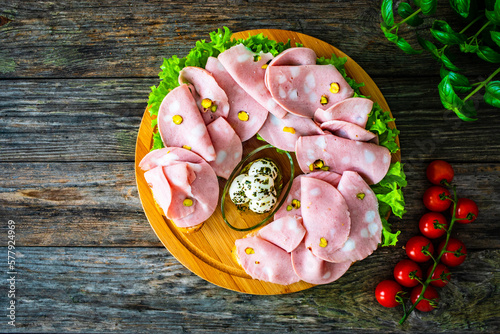 Big sandwich with mortadella with pistachios and lettuce on wooden table 