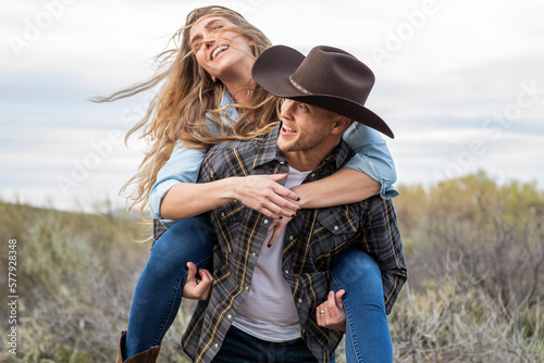 Western wear young couple enjoying piggy back ride on ranch photo