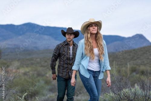 Western wear young couple on desert ranch walking on trail
