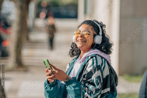 girl with headphones and mobile phone or smartphone on the street