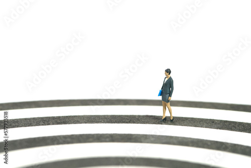 Miniature people toy figure photography. Career track concept. A businesswoman walking on dartboard. Isolated on white background