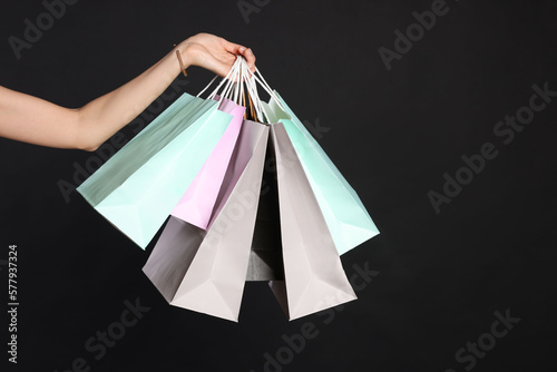 Woman holding shopping bags on black background, closeup. Big sale