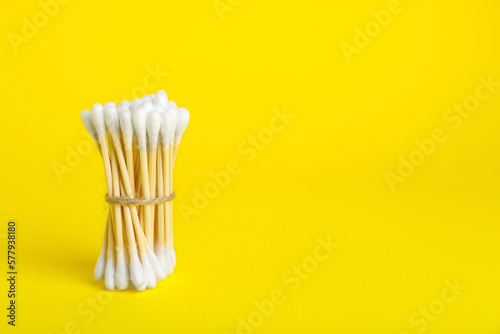 Bunch of new cotton buds on yellow background. Space for text