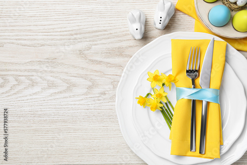 Photography Festive table setting with painted eggs and cutlery on white wooden background, flat lay with space for text