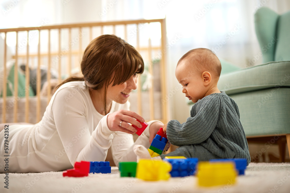 Mother and her baby boy playing with colored toy blocks at home Mother and her baby boy playing with colored toy blocks at home