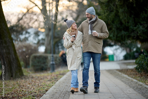 A happy romantic couple with coffee walking in the park