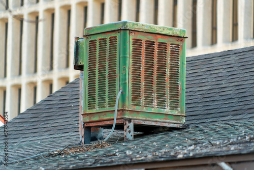 Swamp cooler air condition system on rooftop in modern city with green color and aged and weathered metal body