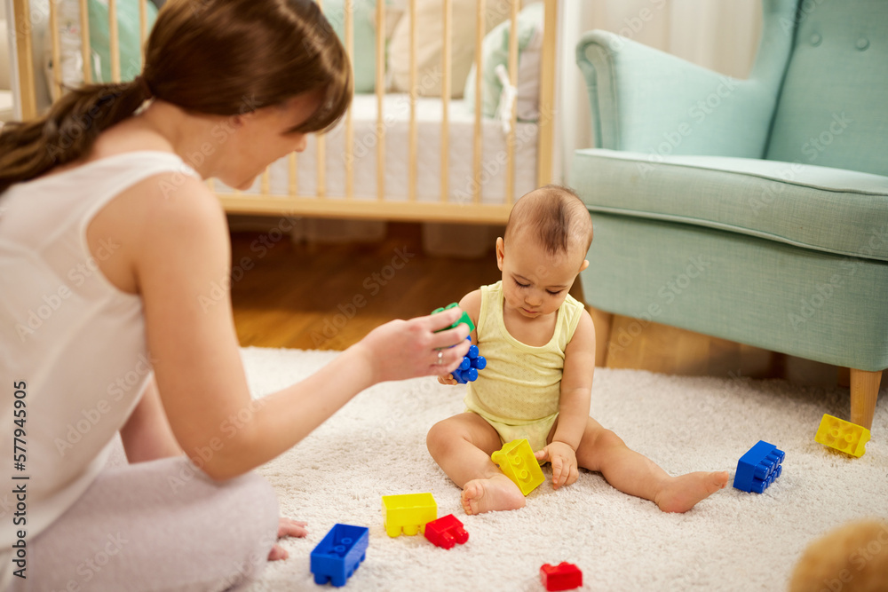 Mother and her baby boy playing with colored toy blocks at home Mother and her baby boy playing with colored toy blocks at home