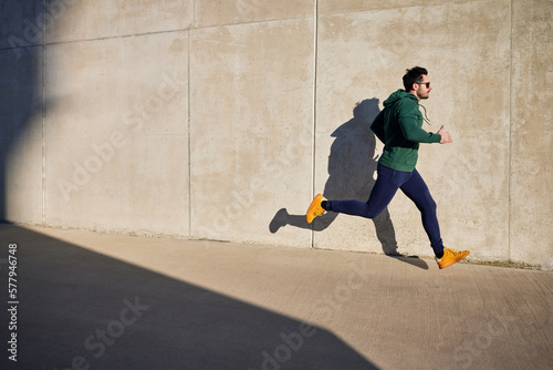 Wallpaper Mural Man running during sunny afternoon in the city next to concrete wall. Active lifestyle concept Torontodigital.ca
