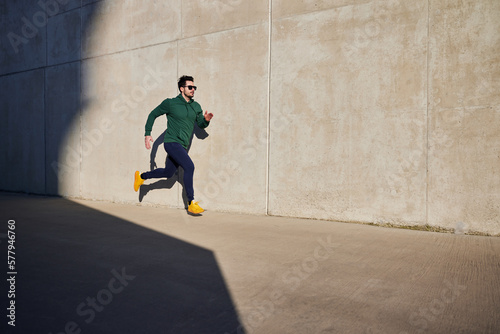 Man running on the street on sunny afternoon wearing sunglasses and sports clothes