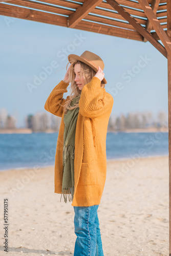 Woman in wool yellow cardigan, fedora hat and blue jeans at the beach, new collection, fashionable trend © T.Den_Team