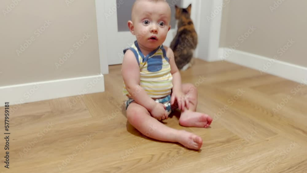 baby sitting relaxed on the floor looking at the camera. baby learns to sit on the floor. happy family kid concept. little baby newborn sitting on the floor in the hallway look at the camera dream