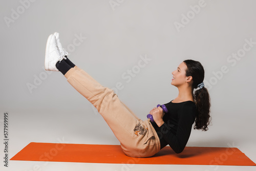 Fitness model exercises with dumbbells and drinks water from a sports bottle