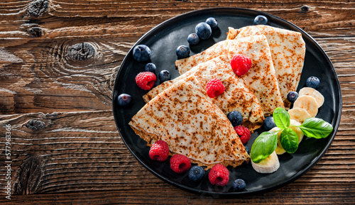 A plate of pancakes with cheese and fruits photo