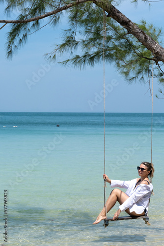 girl resting near the sea on a swing, blue sea