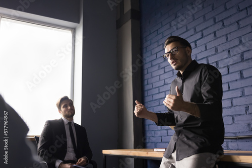 Tableau sur toile Serious stylish male coach giving workshop to group of employees, interns