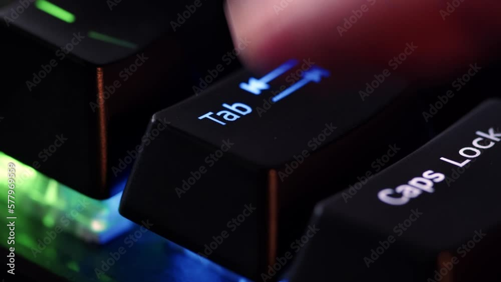 Human finger is clicking on the Tab button on the computer keyboard, close up view. The finger presses Tab on the keyboard key, macro shot. Loop footage.