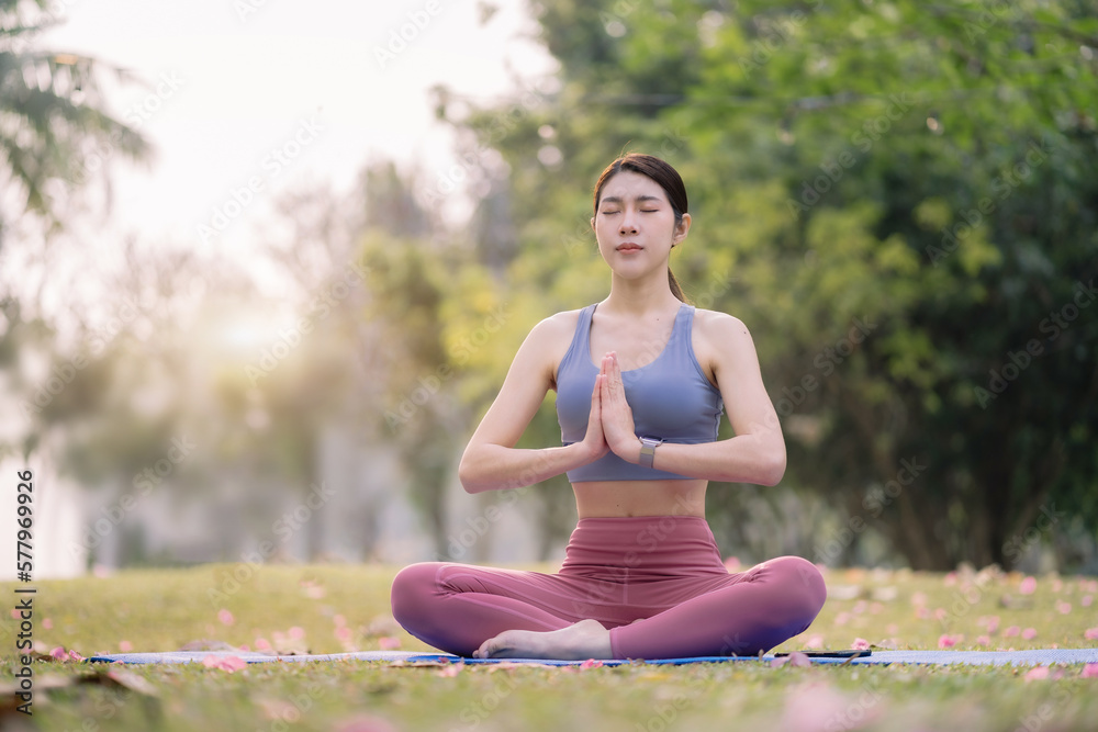 Asian young women practicing yoga In the prayer position and raised hands while sitting on mat at park, Concept of relaxation and meditation. Asian young women practicing yoga In the prayer position and raised hands while sitting on mat at park, Concept of relaxation and meditation.