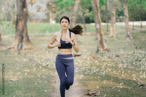 Asian woman running in park.