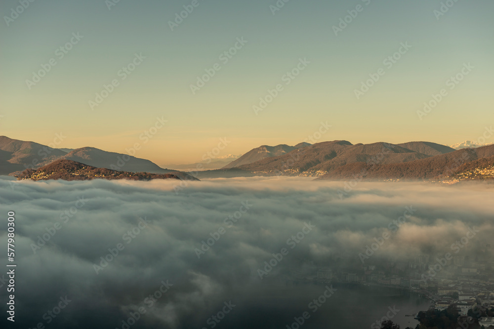Mountain Range Above Cloudscape and Lake Lugano with Sunlight and Clear Sky in City of Lugano, Ticino in Switzerland.