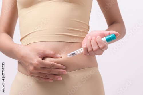 Close up woman using IVF treatment injection on belly to prepare reproductive fertility , Ovulation stimulation ..