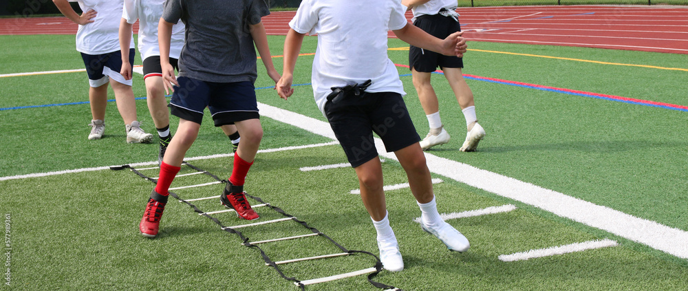 Young football players at summer training camp running in the ladder drill