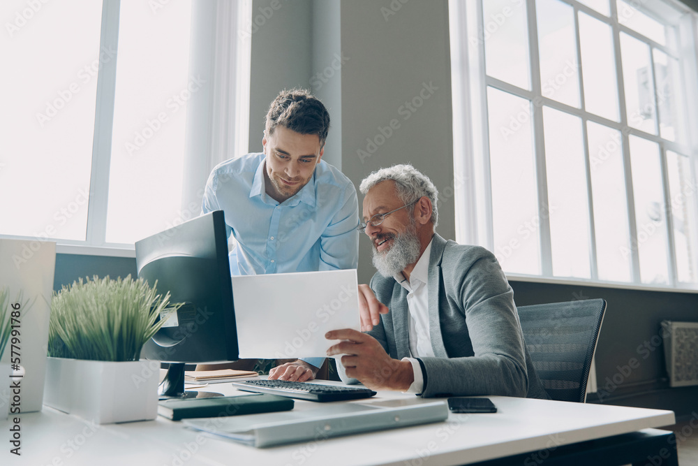 Two confident men doing some paperwork while spending time in the office together