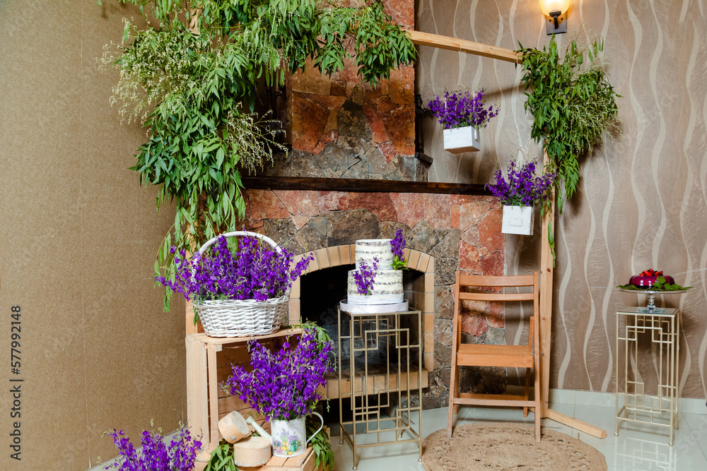 A birthday interior decoration with lavender flowers and a tasty cake in front of the fireplace