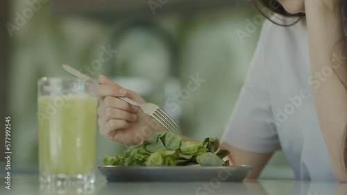 Sad girl close-up trying eat salad and healthy food. Girl does not like eat green lettuce leaves. Slow motion